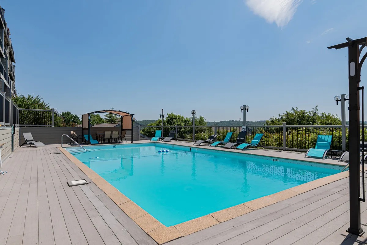 This exterior image features a sparkling swimming pool surrounded by lounge chairs and a canopy structure. The scene exudes a leisurely, family-friendly vibe, ideal for enjoying sunny afternoons or sunset gatherings. The pool's proximity to the condos is suggested by the surrounding resort elements.