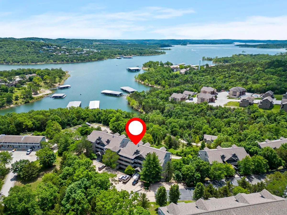A serene lake bordered by lush greenery with several boathouses dotting the shore. The calm water is perfect for boating and fishing, and the overall scene evokes a sense of lakeside adventure and relaxation.
