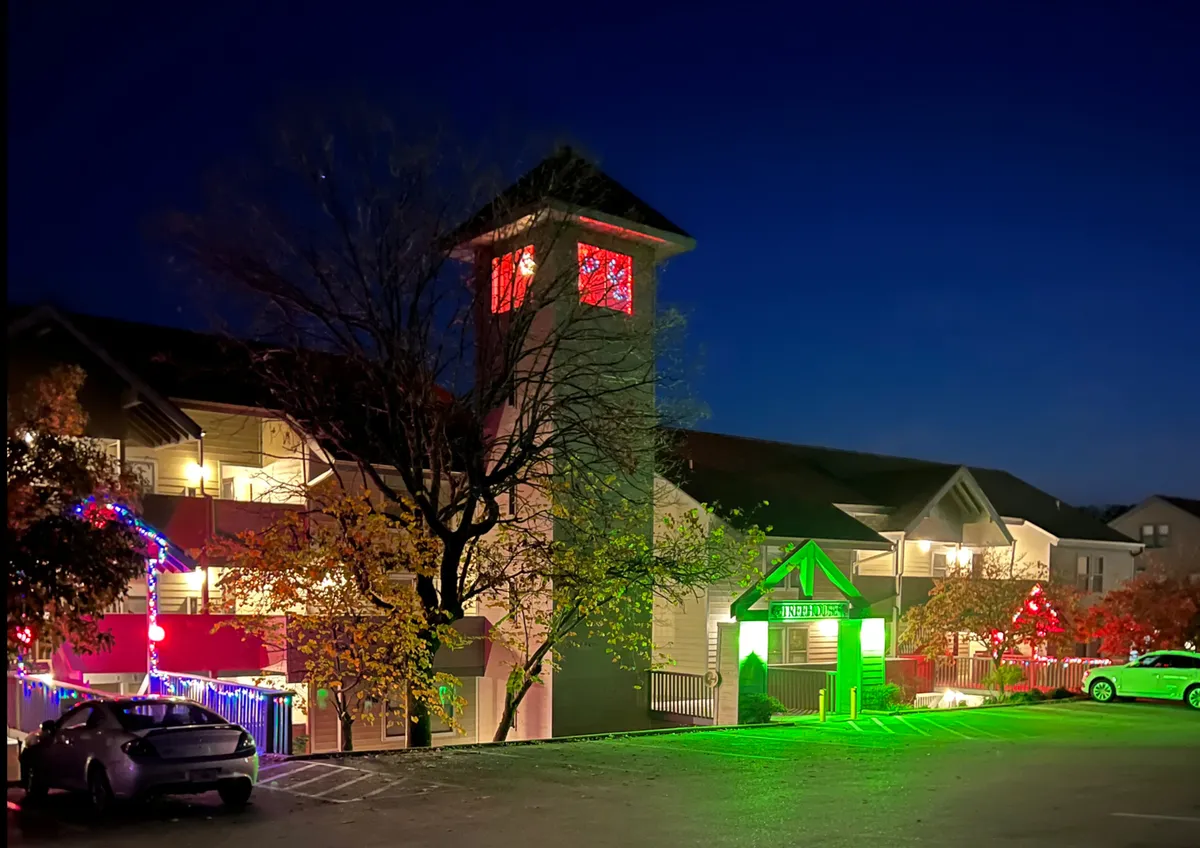 This exterior shot features a welcoming entrance tower with windows aglow and festive green and red decorative lights. The prominent entrance sign and holiday decorations create an inviting and lively ambiance, hinting at the resort-style accommodation awaiting guests after their Branson adventures.