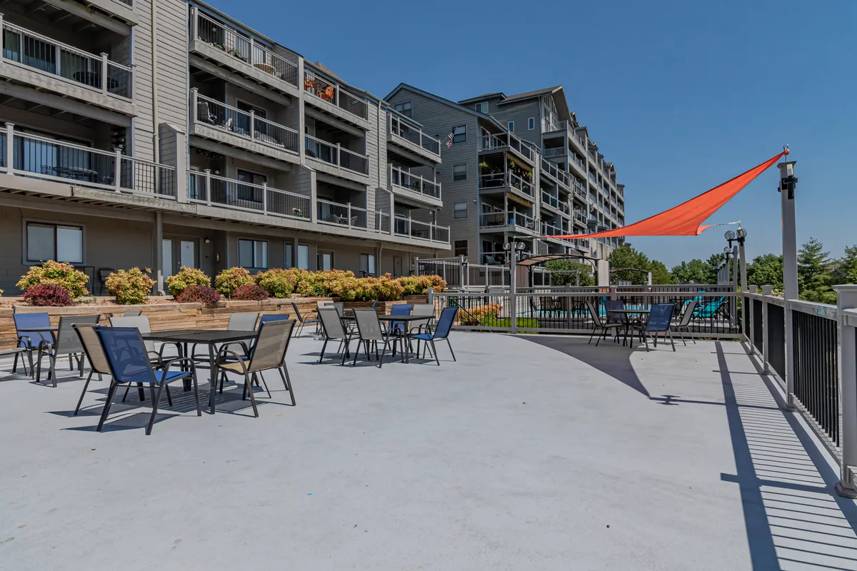An exterior shot featuring an outdoor seating area under a shade sail, surrounded by landscaped planters. The setting is ideal for relaxing, socializing, or savoring quiet moments while overlooking the surrounding area.