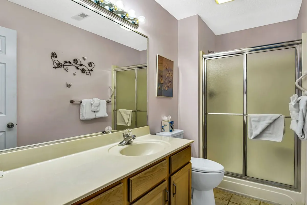 A modern bathroom with a vanity, sink, shower stall, and decorative wall art. Clean lines and a calm palette create a refreshing environment for self-care.