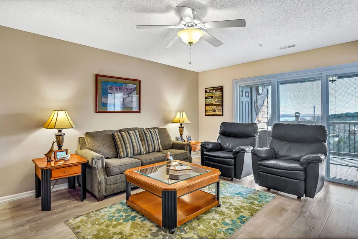 A comfortable living space just beyond the entryway, featuring a sofa, coffee table, armchairs, and windows that fill the room with natural light. The arrangement encourages relaxation and seamless movement from one area to another.