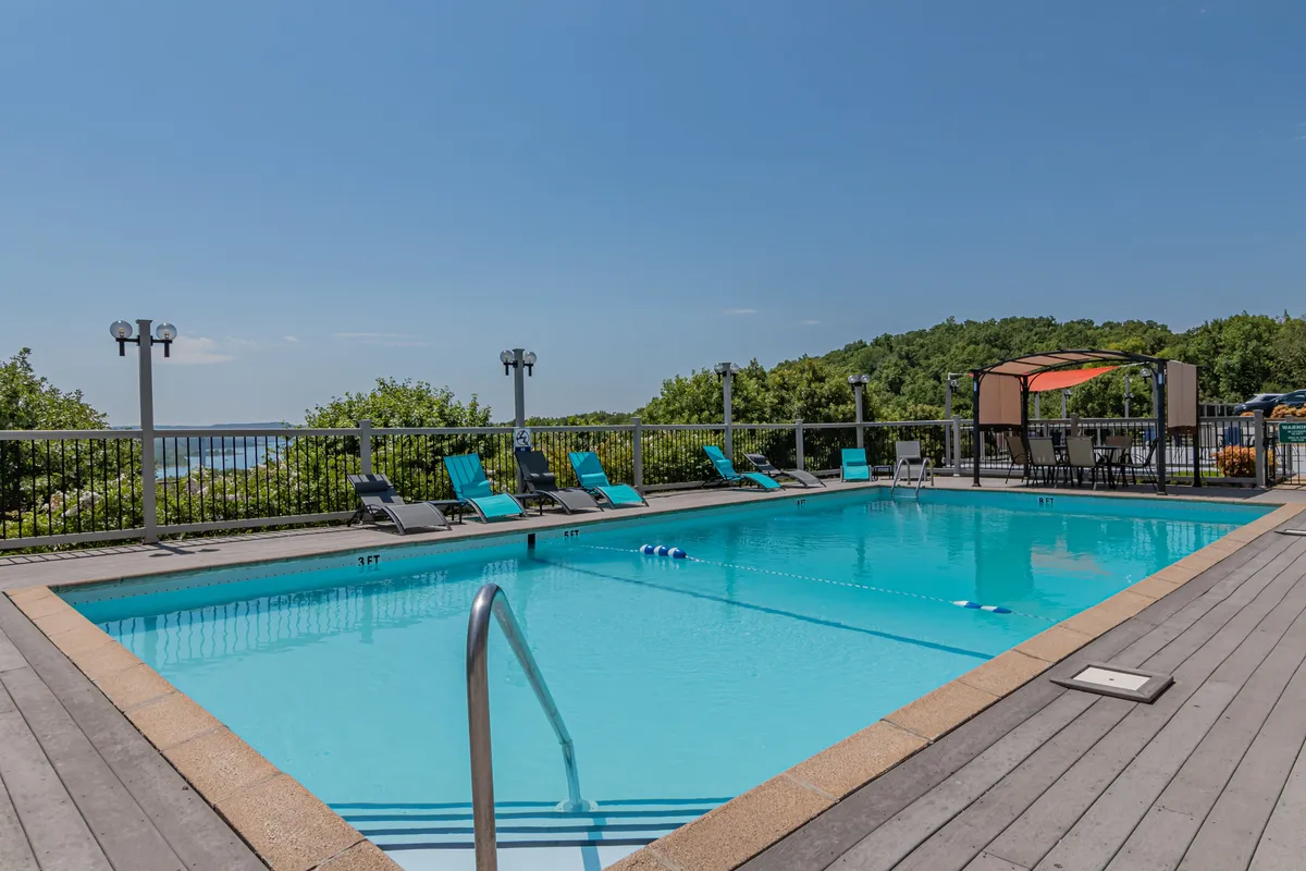 A vibrant outdoor pool scene with inviting lounge chairs and lush greenery nearby. The proximity of the pool to the building is evident, showing guests how easy it is to access resort amenities for relaxation or family fun.